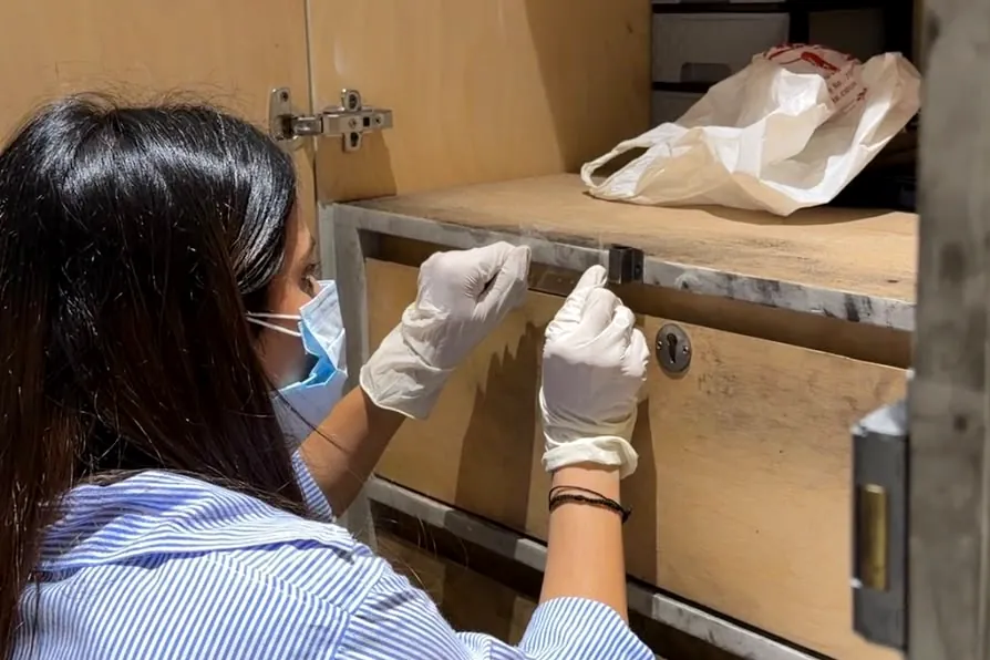 Examiner lifting latent fingerprints from a cabinet drawer